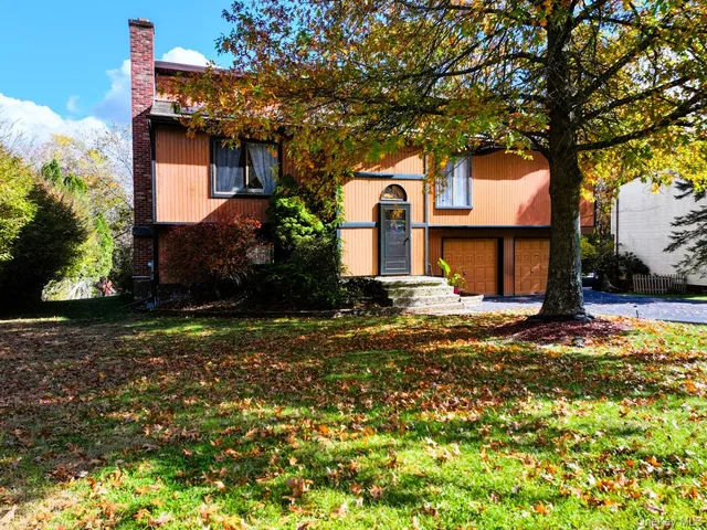 a front view of a house with a yard garage and trees