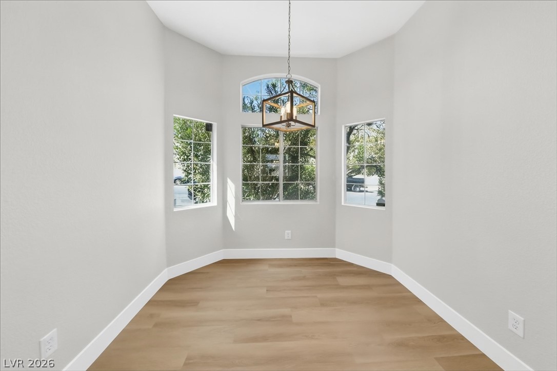 1906 Cardinal Point Street Henderson, NV 89012 - Photo 7 of 20 Arched windows frame garden views, illuminating the polished wood floors in this inviting space.