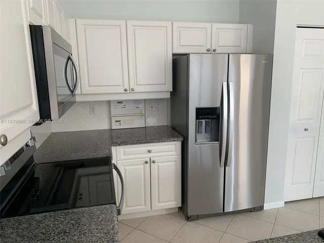 a kitchen with stainless steel appliances granite countertop a refrigerator and a stove top oven