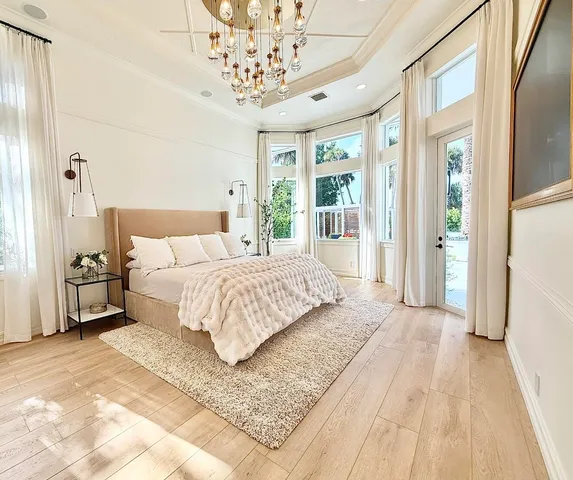 a bedroom with a large bed a chandelier and a window
