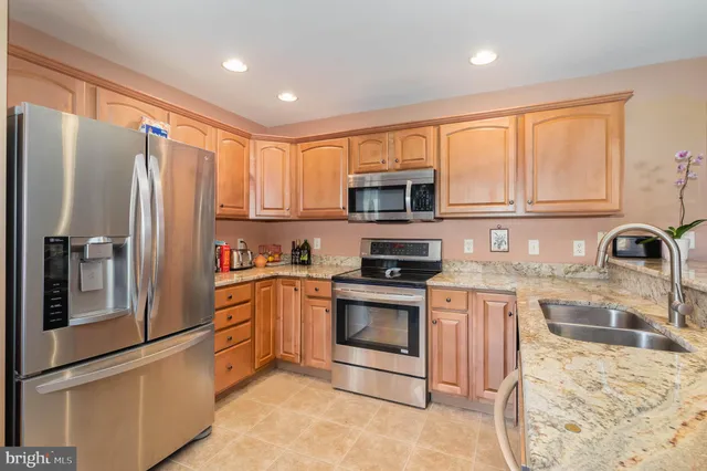 a kitchen with stainless steel appliances granite countertop a refrigerator stove microwave and sink