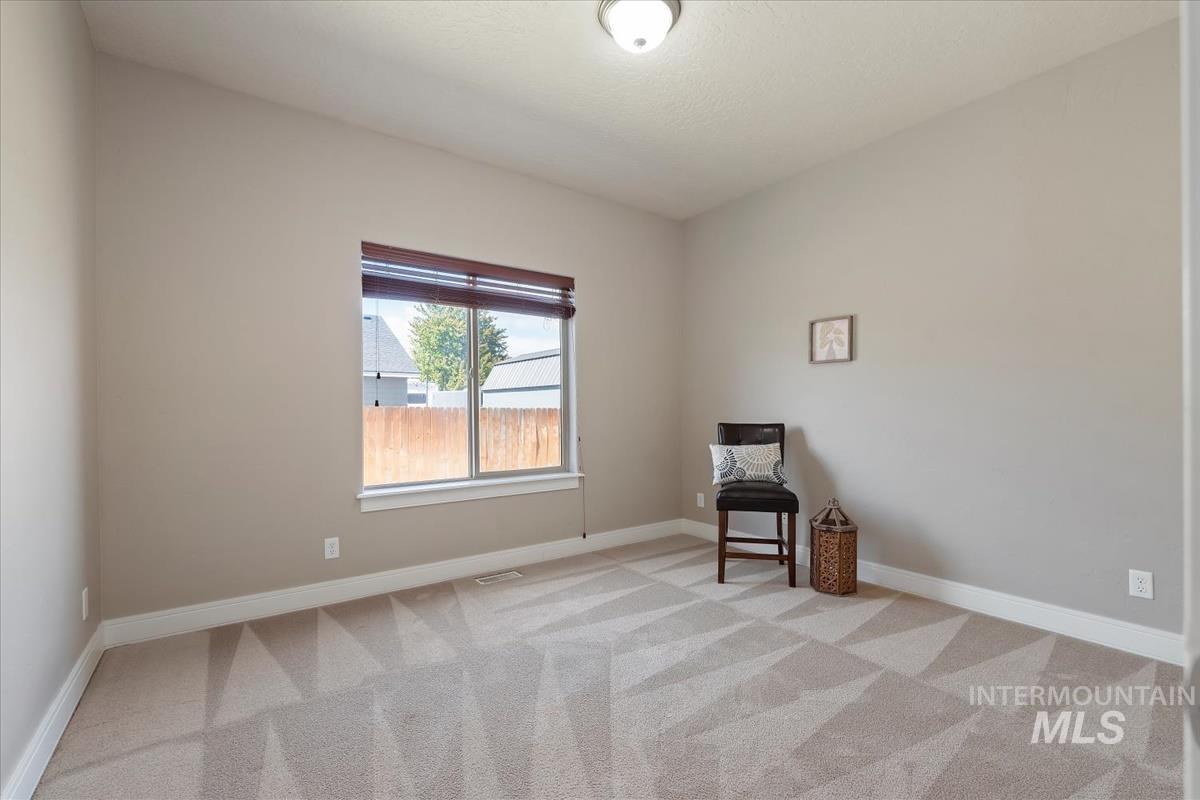 640 Southwest Miner Street Mountain Home, ID 83647 - Photo 15 of 35 Carpeted room with a vaulted ceiling, a single window featuring wood blinds, and neutral-toned wall paint