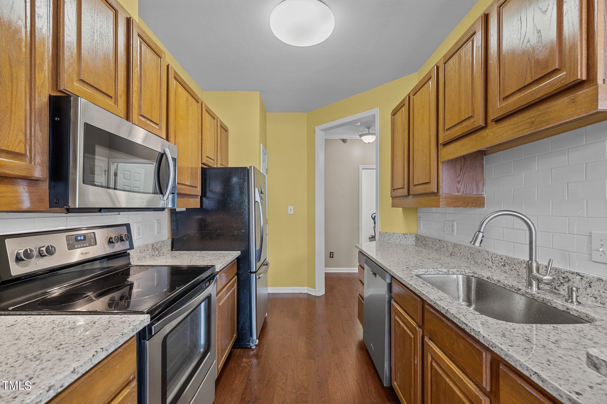 1710 Tiffany Bay Court, Unit 301 Raleigh, NC 27609 - Photo 12 of 36 a kitchen with stainless steel appliances granite countertop a sink a stove and a refrigerator