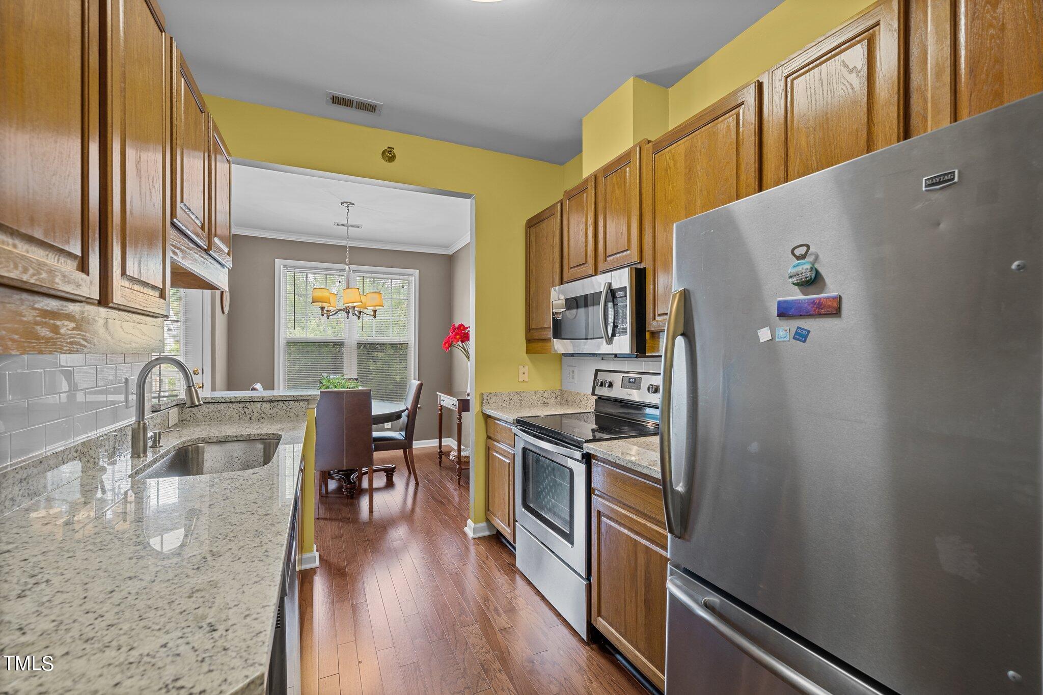 1710 Tiffany Bay Court, Unit 301 Raleigh, NC 27609 - Photo 13 of 36 a kitchen with stainless steel appliances granite countertop a refrigerator a stove and a sink with wooden floor