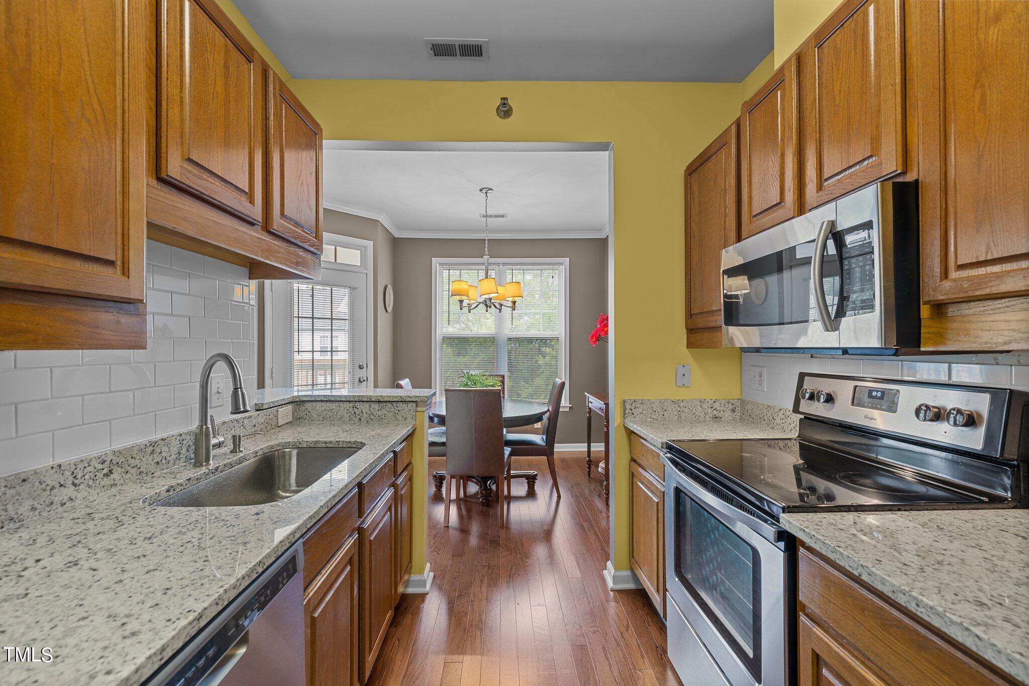 1710 Tiffany Bay Court, Unit 301 Raleigh, NC 27609 - Photo 14 of 36 a kitchen with stainless steel appliances granite countertop a sink a stove and a wooden cabinets