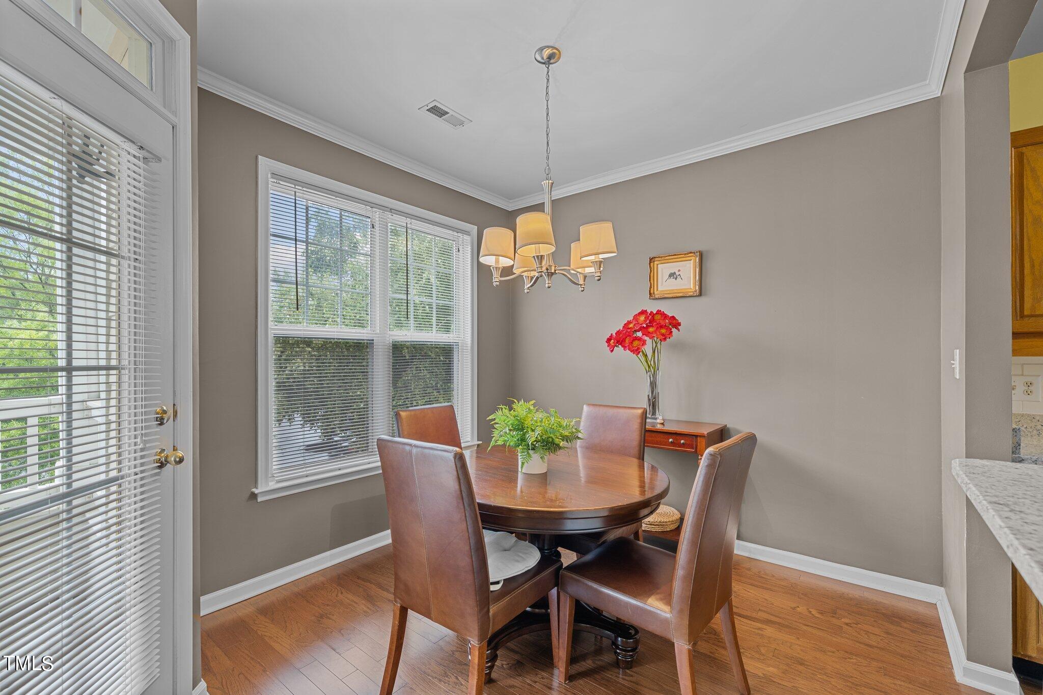 1710 Tiffany Bay Court, Unit 301 Raleigh, NC 27609 - Photo 7 of 36 a dining room with furniture potted plants and wooden floor