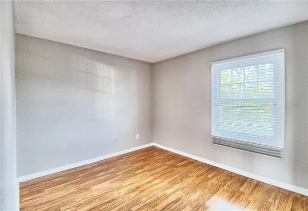 a view of an empty room with window and wooden floor
