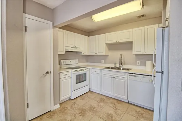 a kitchen with white cabinets and white appliances