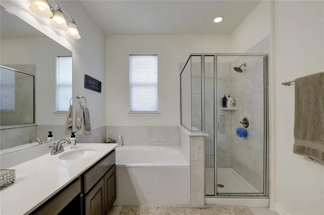 a bathroom with a bath tub sink mirror and shower
