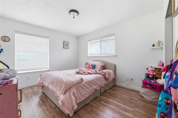 a bedroom with a bed potted plant on the dresser and a window