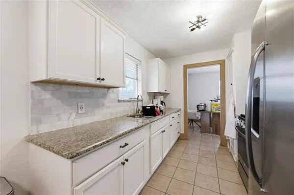 a kitchen with granite countertop a sink stainless steel appliances and white cabinets