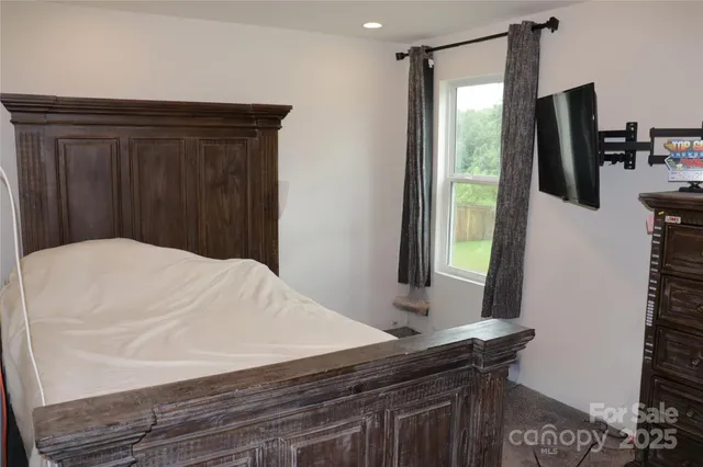 a bedroom with a bed and a flat tv screen on dresser