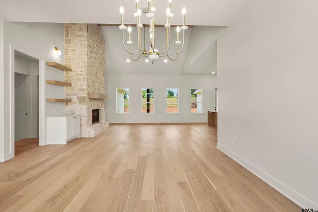 a view of a hallway with wooden floor and chandelier
