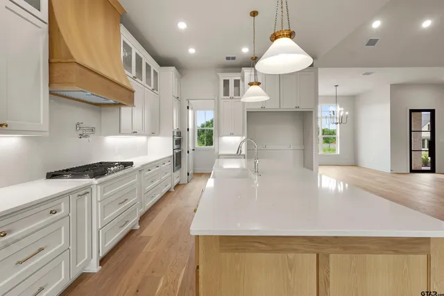 a large kitchen with stainless steel appliances granite countertop a lot of counter space and wooden floors
