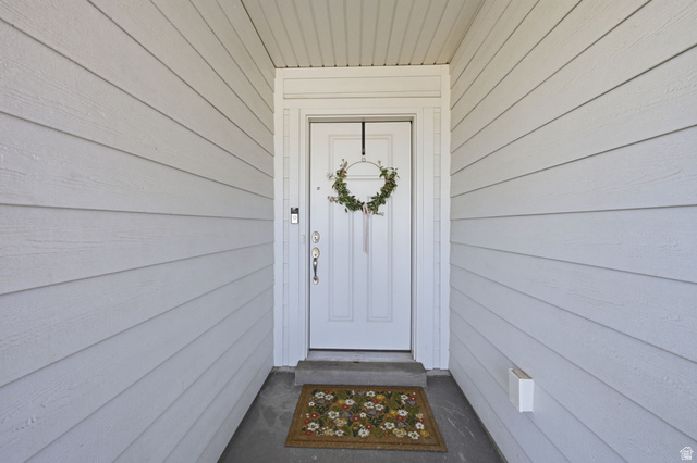 1175 Silver Hollow Road Syracuse, UT 84075 - Photo 5 of 34 Entryway featuring white panel siding, a white front door with a full-view storm door, and a covered porch with a concrete slab