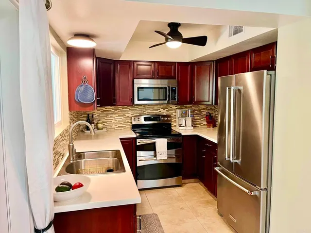a kitchen with stainless steel appliances granite countertop a refrigerator a stove and a sink with dishwasher