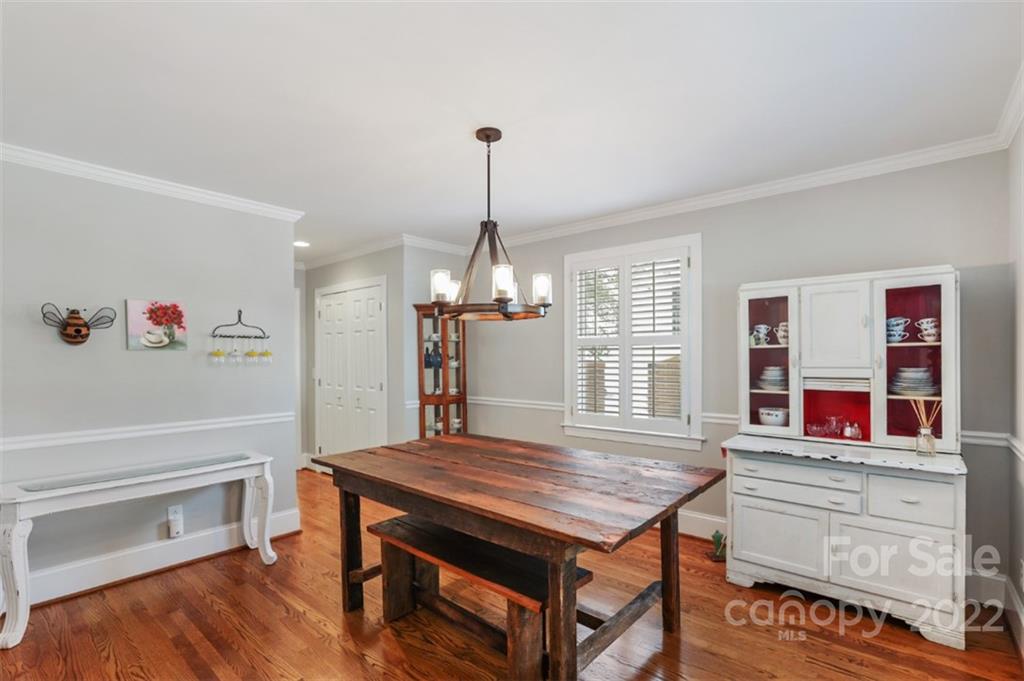 1023 Sedgefield Road Charlotte, NC 28209 - Photo 26 of 40 a dining room with wooden floor a chandelier a wooden table and chairs