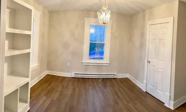 an empty room with wooden floor cabinet and windows