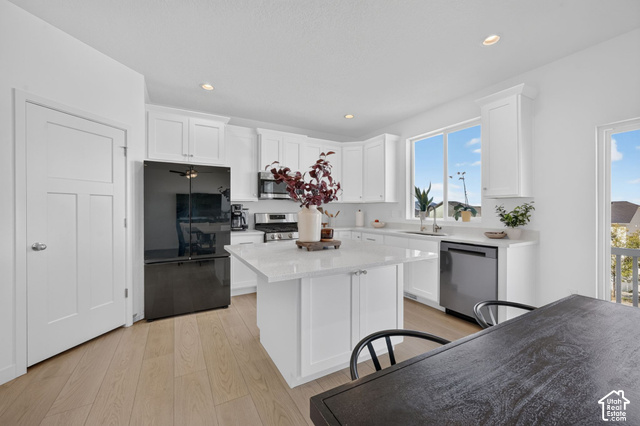 428 Quartz Road Tooele, UT 84074 - Photo 10 of 35 Kitchen featuring white cabinetry, light wood-finish flooring, a central island with a light-toned countertop, stainless steel appliances, and abundant natural light