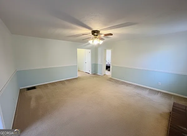 an empty room with windows and fan