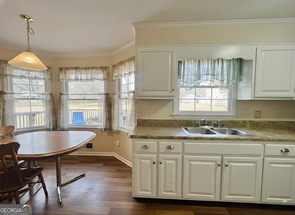 a kitchen with granite countertop a sink cabinets and wooden floor