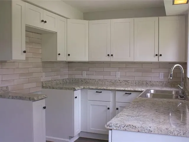 a kitchen with granite countertop white cabinets and a sink