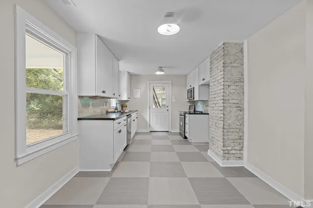 a large white kitchen with a window and stainless steel appliances