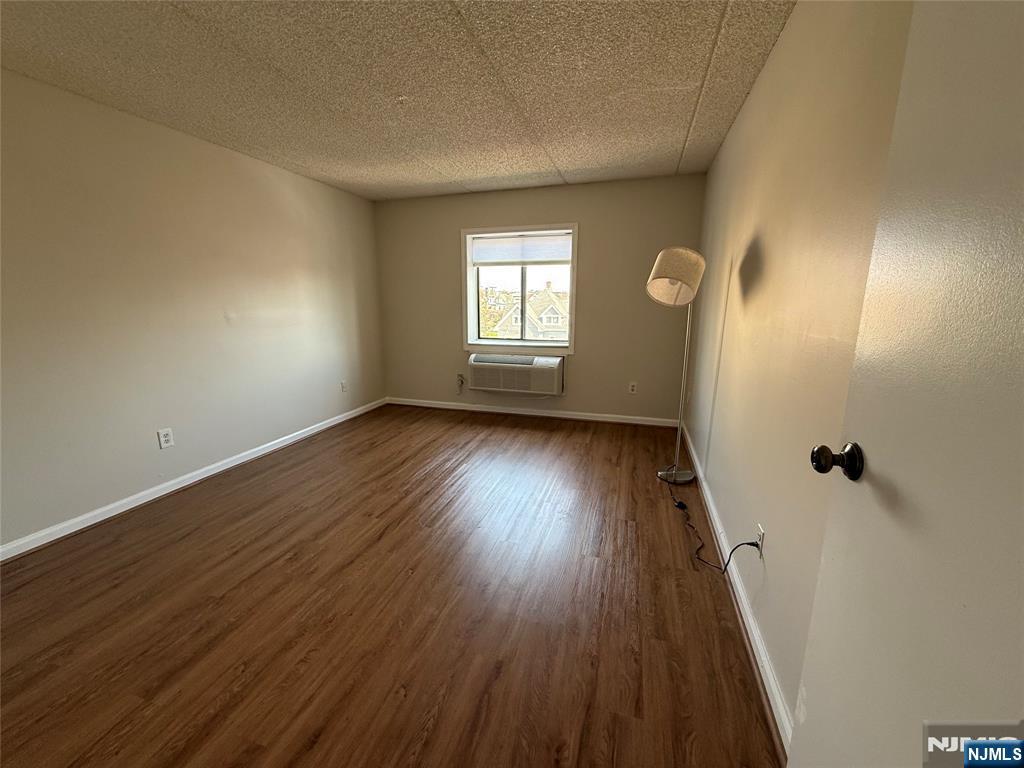 281 Park Street, Unit 3B Hackensack, NJ 07601 - Photo 6 of 11 an empty room with wooden floor and windows