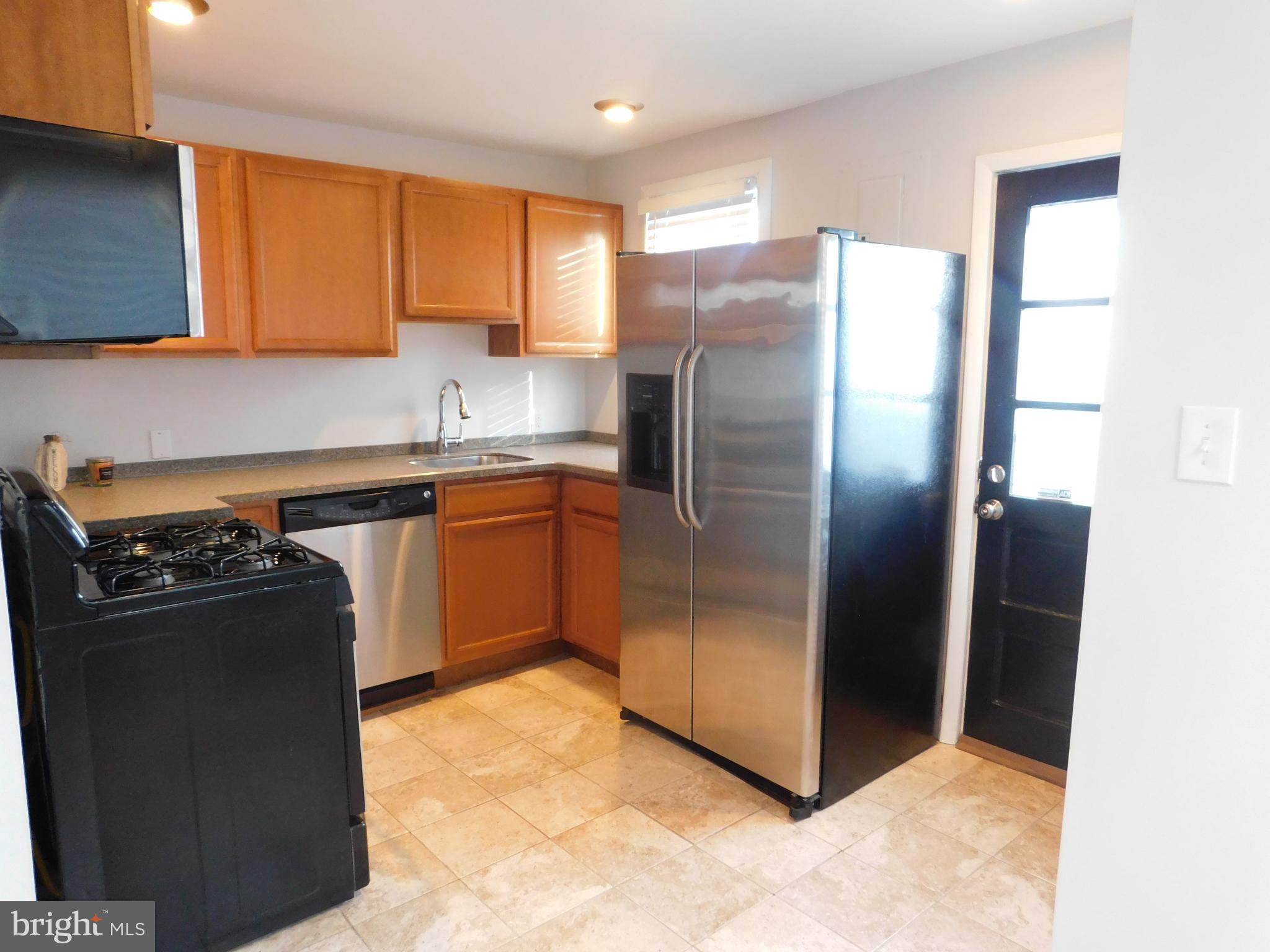 8121 Bullneck Road Baltimore, MD 21222 - Photo 6 of 20 a kitchen with stainless steel appliances granite countertop a refrigerator a sink a stove and wooden cabinets