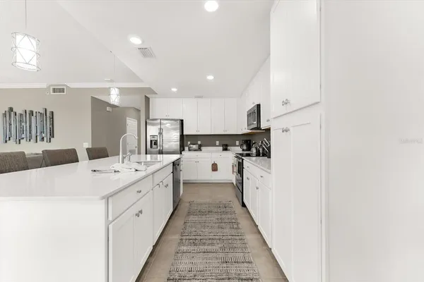 a large white kitchen with a sink and dishwasher a refrigerator with wooden floor