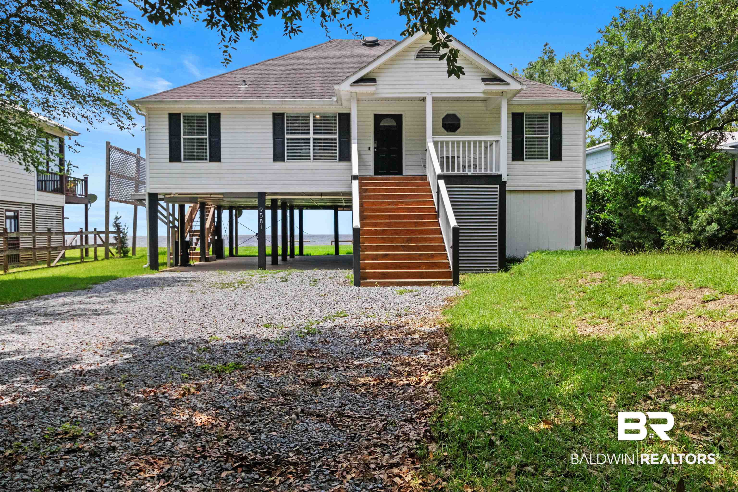 9581 South Bay Street Foley, AL 36535 - Photo 4 of 44 Elevated coastal-style residence featuring white siding, a dark shingle roof, and black window shutters