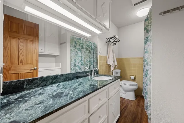 a bathroom with a granite countertop sink a toilet a mirror and shower