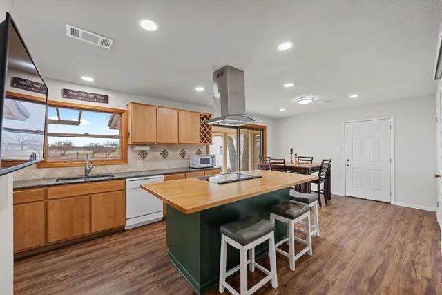 a kitchen with stainless steel appliances granite countertop a table chairs sink and cabinets