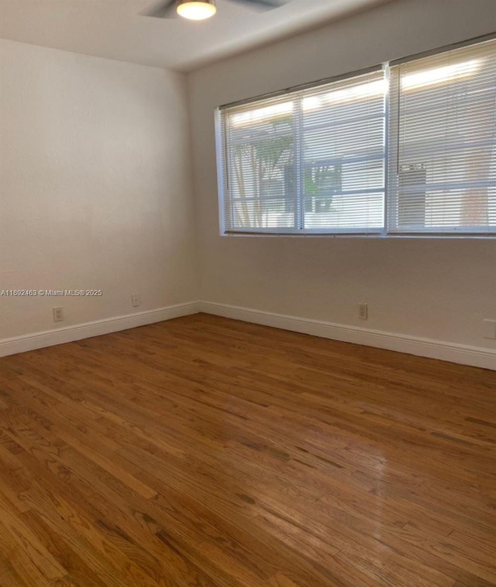 340 84th Street, Unit 2 Miami Beach, FL 33141 - Photo 8 of 10 a view of an empty room with wooden floor and a window