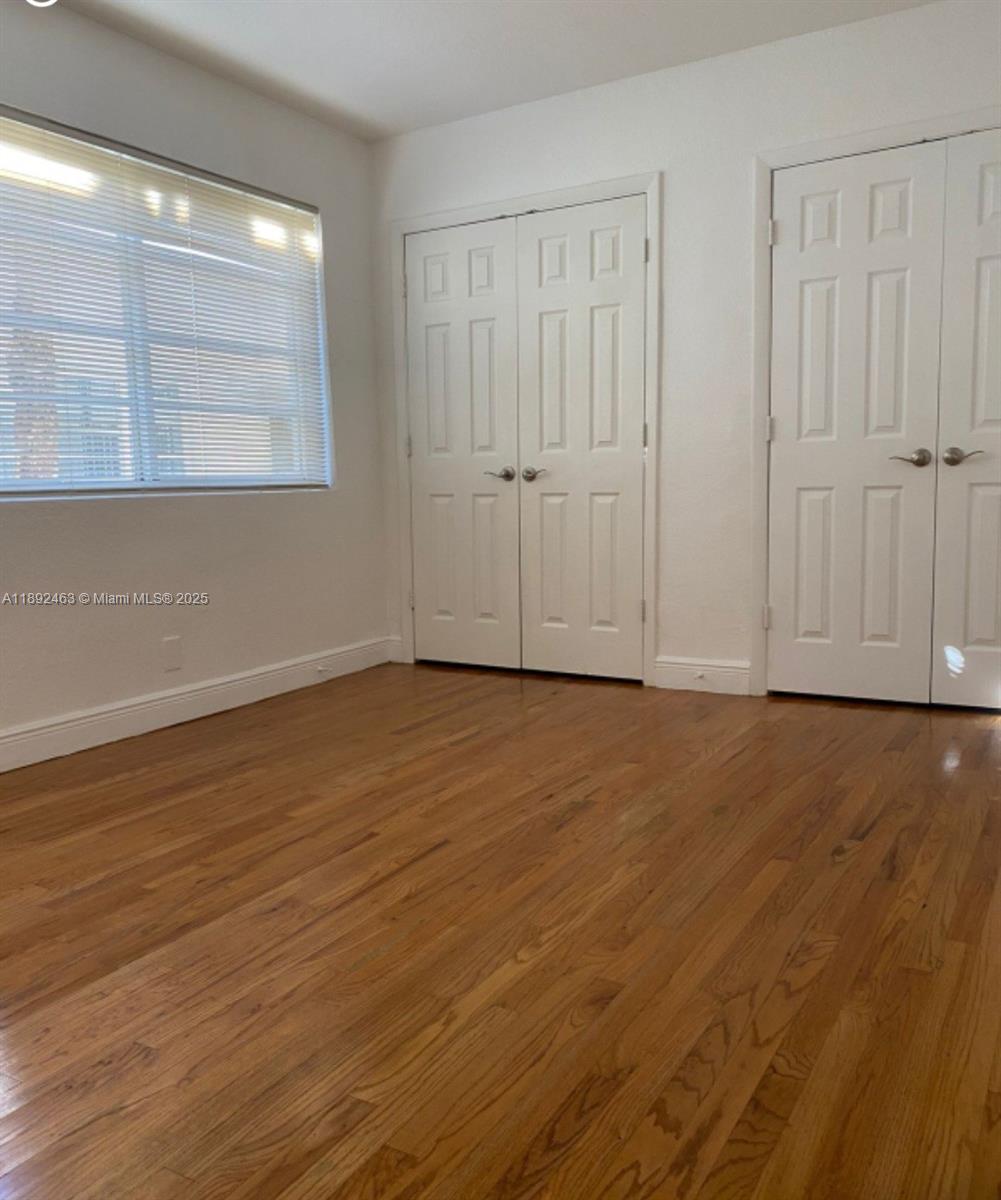 340 84th Street, Unit 2 Miami Beach, FL 33141 - Photo 9 of 10 a view of an empty room with wooden floor and a window