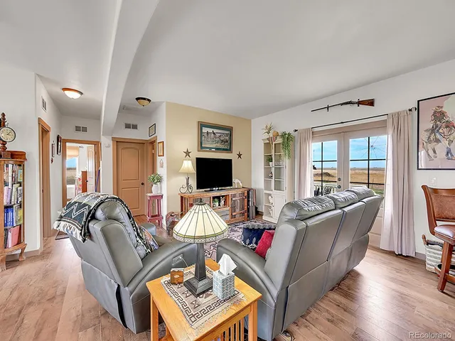 a living room with furniture flat screen tv and a large window