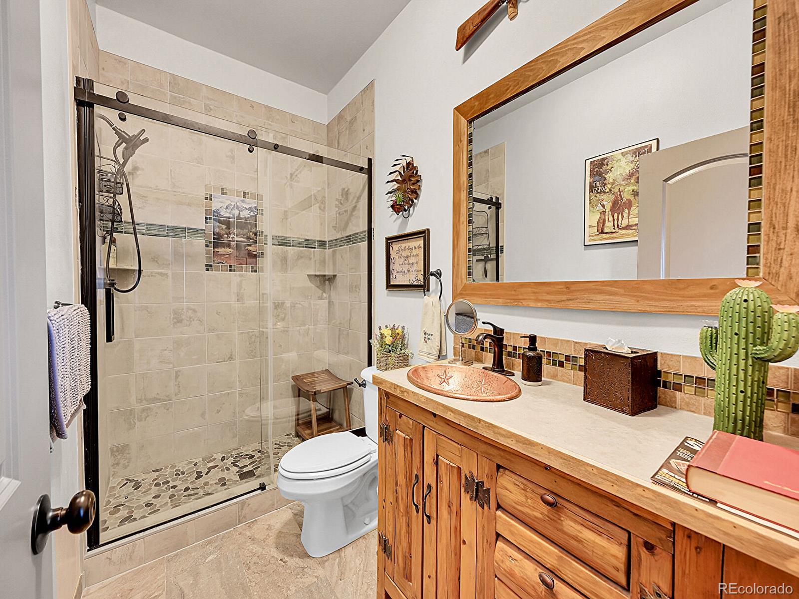 10660 Schumaker Road Bennett, CO 80102 - Photo 15 of 50 a bathroom with a double vanity sink toilet and shower