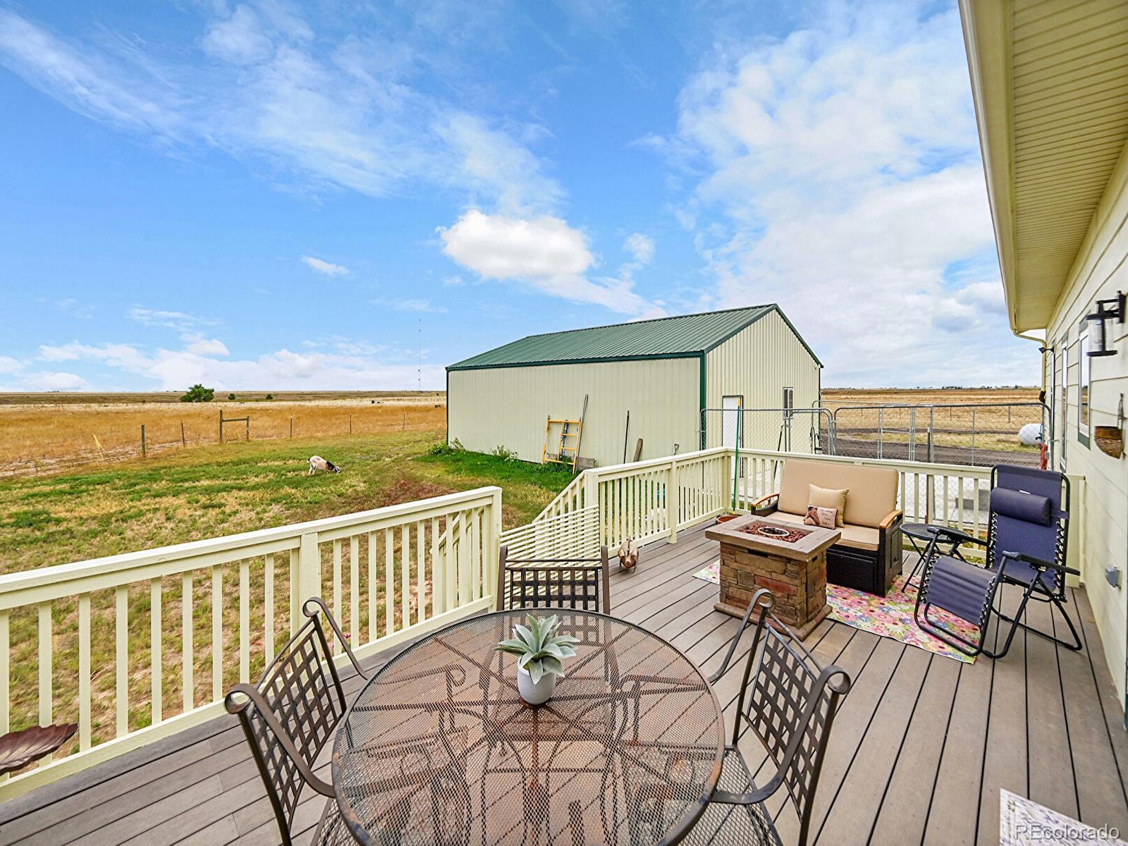 10660 Schumaker Road Bennett, CO 80102 - Photo 25 of 50 a view of a balcony with wooden floor and outdoor seating