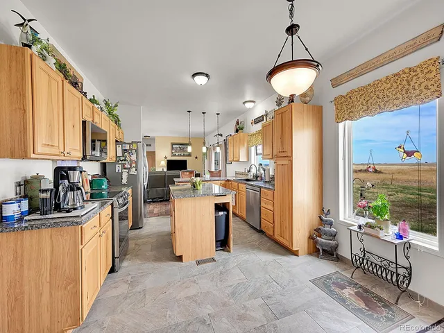 a kitchen with kitchen island granite countertop a sink appliances cabinets and a counter top space