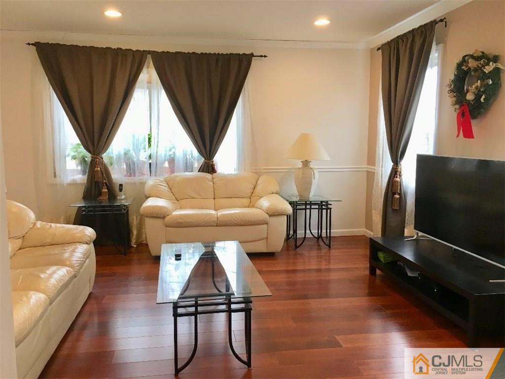 23 Raleigh Road Edison, NJ 08817 - Photo 7 of 19 a living room with furniture a flat screen tv and a floor to ceiling window
