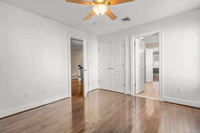 an empty room with wooden floor and a ceiling fan