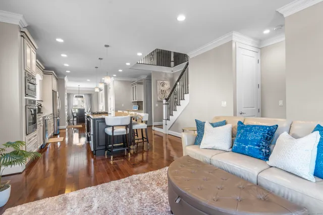 a living room with furniture kitchen view and a wooden floor