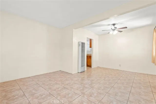 an empty room with chandelier fan and windows