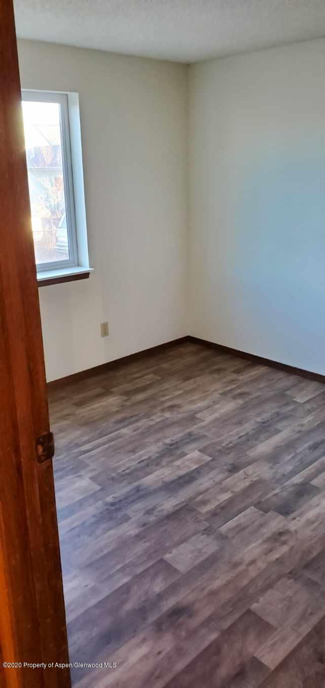 1012-1018 Stillwell Avenue Rifle, CO 81650 - Photo 11 of 15 a view of an empty room with wooden floor and a window