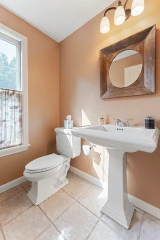 a bathroom with a toilet a sink a mirror and a window