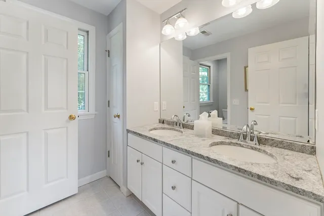 a bathroom with a granite countertop double vanity sink and a mirror