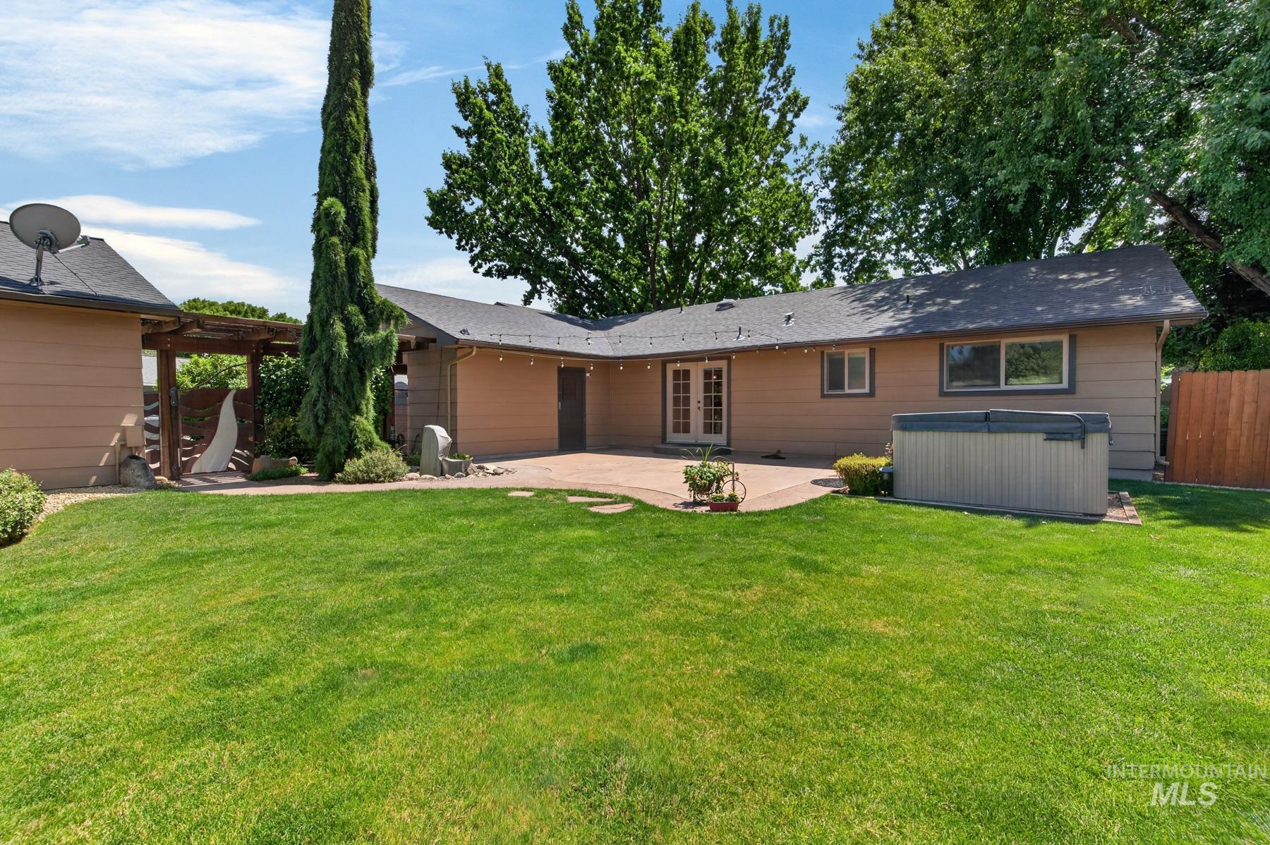 9622 Delaware Street Boise, ID 83709 - Photo 36 of 48 Expansive lawn area featuring a stone patio, French doors, a built-in spa, and mature landscaping