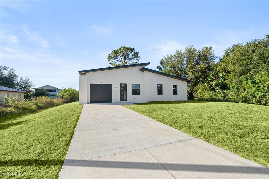 2603 3rd Street Southwest Lehigh Acres, FL 33976 - Photo 2 of 28 a front view of a house with a yard and garage