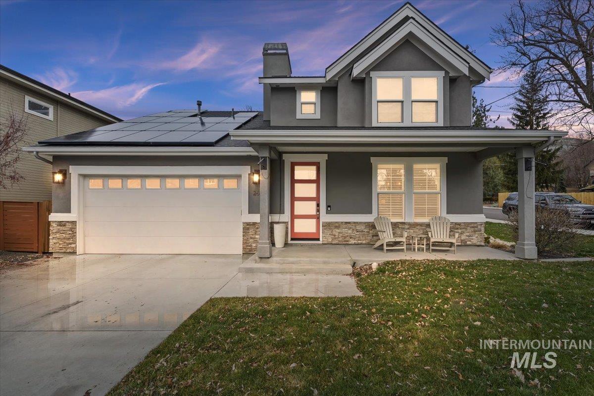 View of front of home with covered porch, stone siding, a front lawn, stucco siding, and roof mounted solar panels