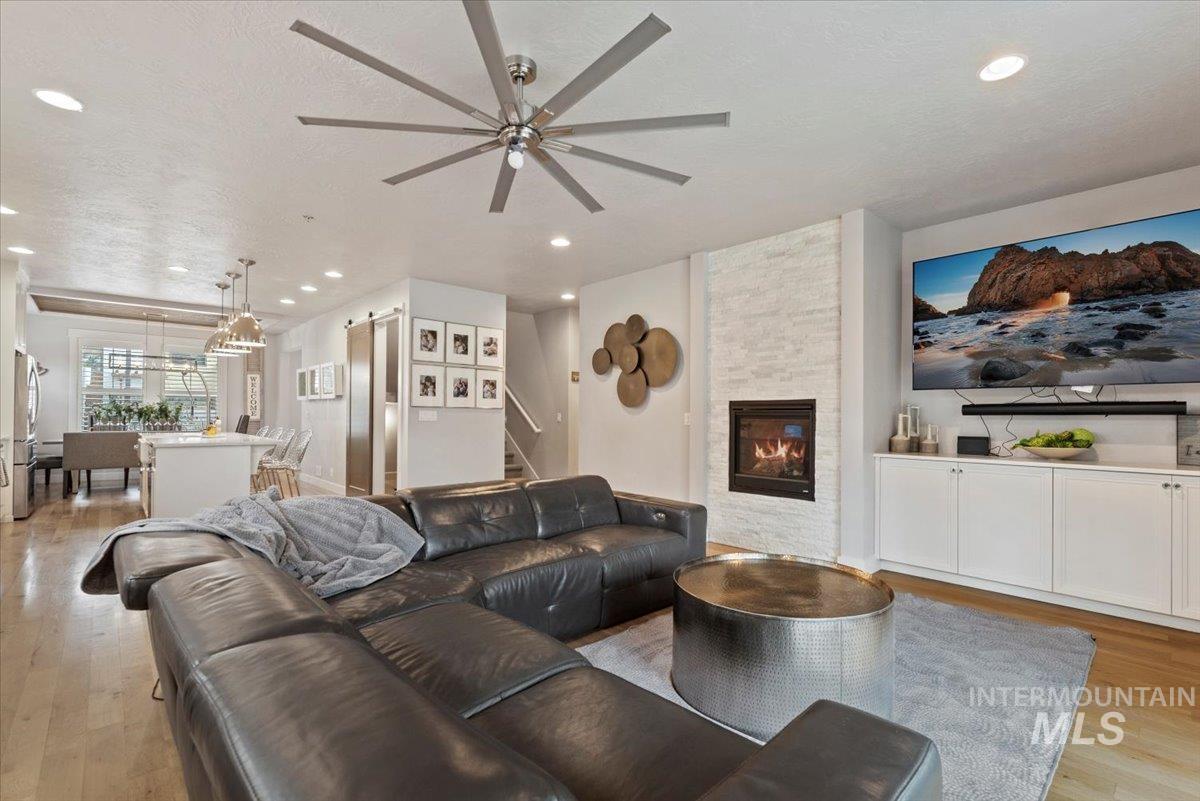 2616 West Neff Street Boise, ID 83702 - Photo 13 of 36 Living room with light wood-style flooring, a stone fireplace, a ceiling fan, recessed lighting, and stairway